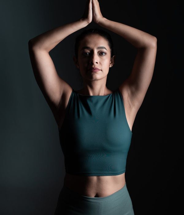 Woman in a calm yoga pose in a studio with green light accents.